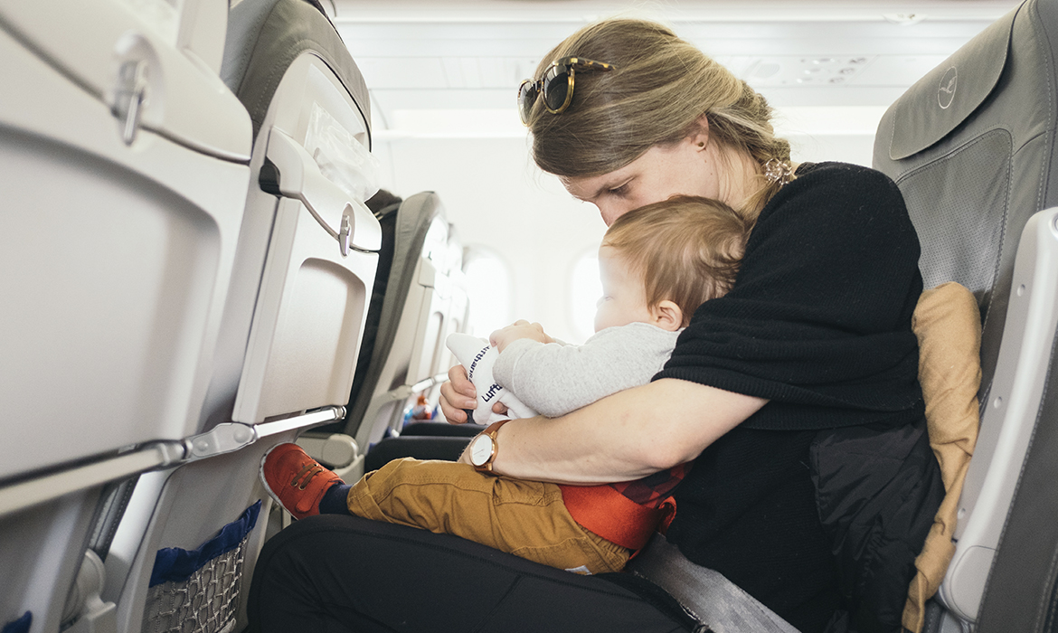 mãe distraindo bebê em seu colo, durante viagem de avião